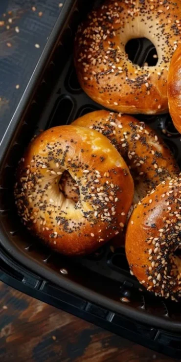 Homemade Air Fryer Bagels garnished with sesame seeds on a wooden table